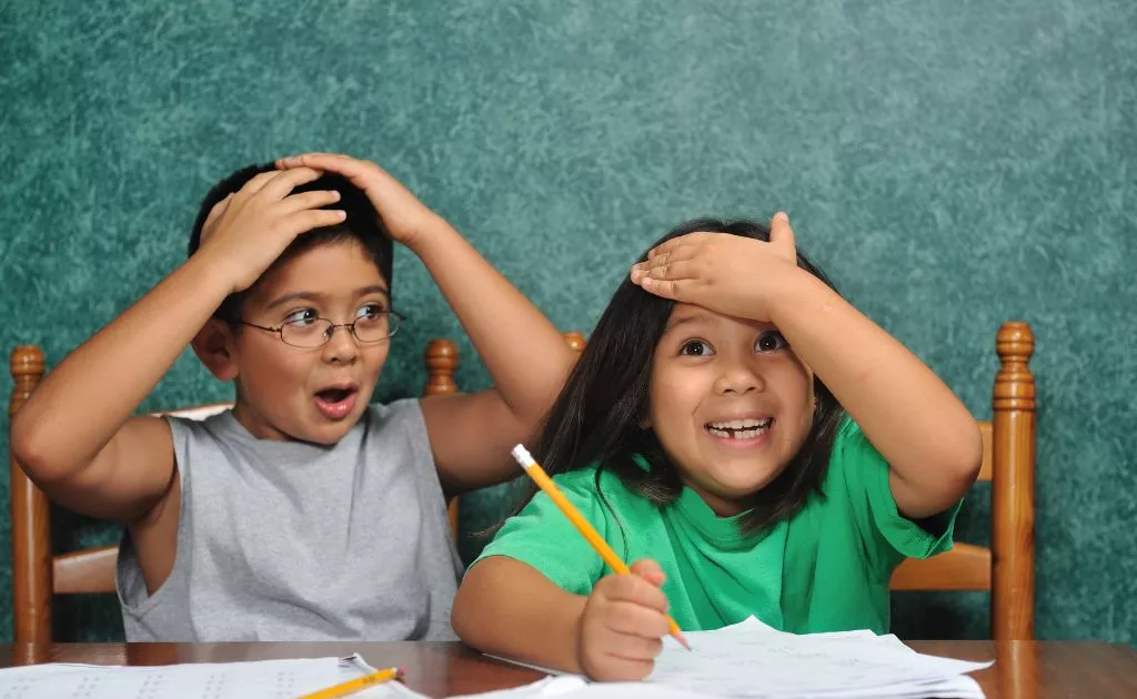 bambini con espressioni simpatiche mentre fanno i compiti